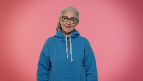Cheerful-lovely-senior-old-gray-haired-woman-in-casual-blue-hoodie-smiling,-looking-at-camera