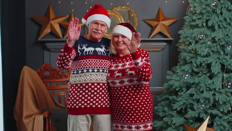 Fröhliche-ältere-Weihnachtsfamilie,-Die-Freundlich-In-Die-Kamera-Lächelt-Und-Mit-Den-Händen-Winkt-Und-Hallo-Oder-Auf-Wiedersehen-Sagt