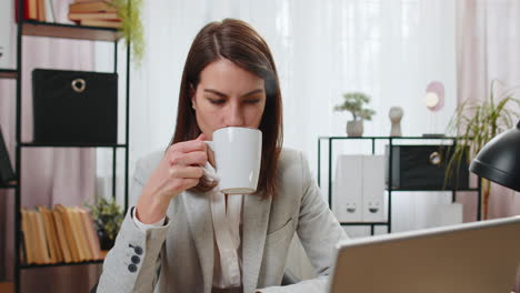 Geschäftsfrau-Trinkt-Eine-Tasse-Warmen-Heißen-Kaffee-Und-Sitzt-Am-Tisch-Im-Büro-Am-Arbeitsplatz.-Entspannen-Sie-Sich-Und-Machen-Sie-Eine-Pause
