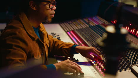 Music-producer-using-audio-mixer-in-professional-studio