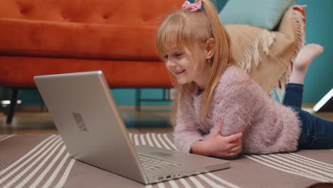 Fröhliches-Schulmädchen-Benutzt-Laptop-Computer-Und-Lernt-Allein-Zu-Hause-Das-Lesen-Von-Online-Unterrichtsstunden