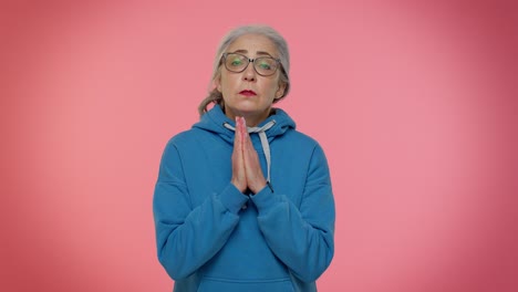 Mature-old-woman-praying-to-God-making-wish-asking-with-hopeful-imploring-expression-begging-apology