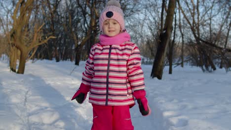 Smiling-child-kid-walking,-having-fun,-relaxing,-looking-around-on-snowy-road-in-winter-park-forest