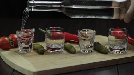 Pour-vodka-into-shot-glasses-placed-on-a-wooden-board