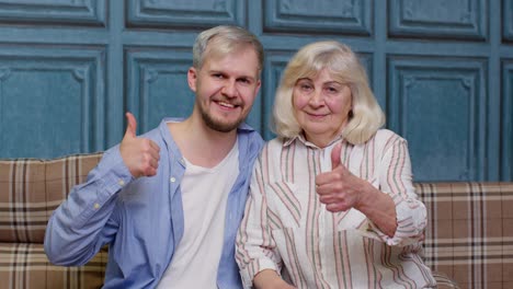 Family-of-senior-gray-haired-mother-and-handsome-adult-son-or-grandson-showing-thumbs-up-gesture