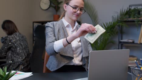 Geschäftsfrau-Erhält-Nach-Erfolgreichem-Finanzgeschäft-Geld-Vom-Laptop-Im-Büro