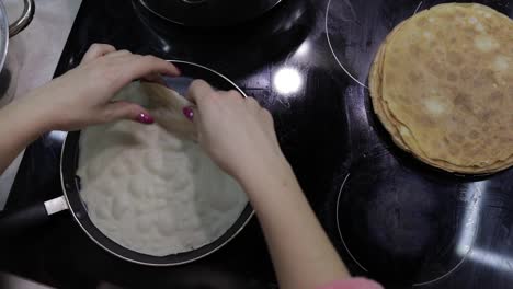 The-process-of-cooking-homemade-pancakes.-Woman-turns-pancake-in-a-frying-pan