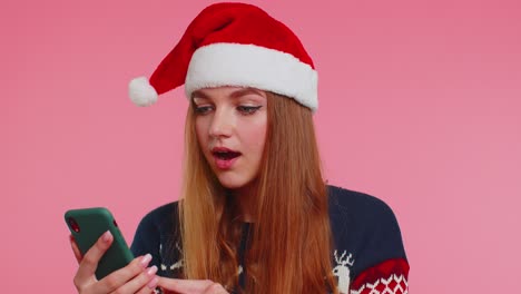 Woman-in-stylish-Christmas-sweater-looking-smartphone-display-sincerely-rejoicing-win-success-luck