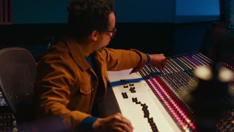 African-american-sound-producer-connecting-coiled-cable-on-mixing-console