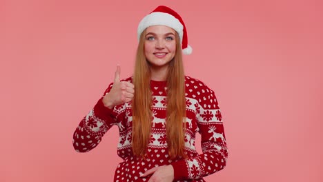 Funny-girl-wears-red-New-Year-sweater-raises-thumbs-up-agrees-something-good,-like,-pink-background