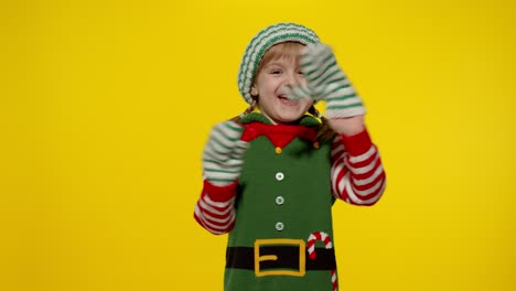 Mädchen-Im-Weihnachtselfenkostüm-Als-Weihnachtsmannhelfer-Winkt-Zur-Begrüßung-Mit-Der-Hand.-Hallo,-Hi,-Grußgeste