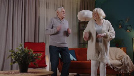 Sorglose-Seniorenpaare-Tanzen-Zu-Hause-Und-Haben-Spaß-Mit-Moderner-Musik,-Die-Zu-Hause-Lächeln