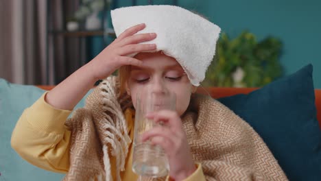 Child-girl-in-plaid-suffering-from-cold-or-allergy,-drinking-medicine-pill-tablet-water-at-home-room