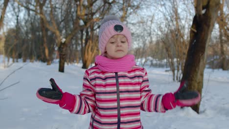 Smiling-child-kid-walking,-having-fun,-relaxing,-looking-around-on-snowy-road-in-winter-park-forest