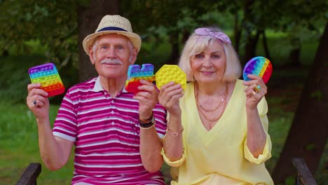 Lächelnde-ältere-Alte-Großmutter-Großvater-Hält-Anti-Stress-Touchscreen-Push-Pop-Es-Beliebtes-Spielzeug