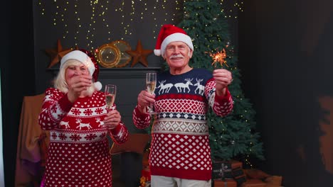 Smiling-senior-grandparents-family-couple-holding-Christmas-bengali-sparkles,-glasses-of-champagne