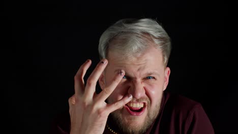 Portrait-of-angry-annoyed-young-man-screaming-to-the-camera-with-raised-hand-on-black-background