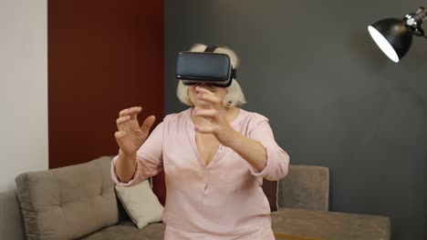 Ältere-Großmutter-Mit-Virtueller-Headset-Brille,-Die-Zu-Hause-Erstaunliche-3D-Videos-Im-VR-Helm-Anschaut