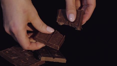 Woman-breaks-black-chocolate-bar-with-nuts.-Close-up.-Slow-motion
