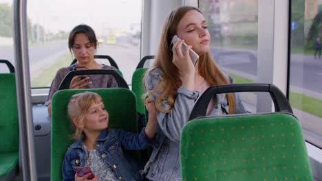 Young-family-woman-with-kid-girl-sitting-in-public-bus-transport,-mother-talking-on-mobile-phone