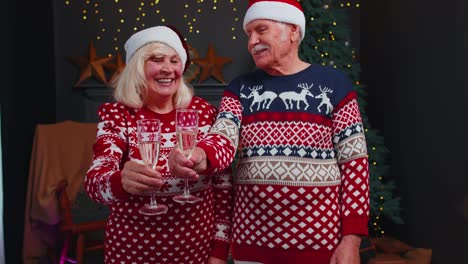 Happy-senior-family-couple-celebrating-Christmas-at-home,-clinking-glasses-and-drinking-champagne