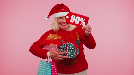 Senior-woman-in-Christmas-sweater-showing-gift-box-and-90-Percent-discount-inscriptions-banner-text