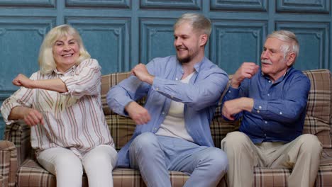 Happy-generation-family-of-senior-grandparents-with-adult-son-listening-to-music,-dancing-at-home