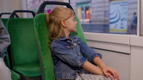 Attraktives-Kleines-Mädchen,-Das-Im-Modernen-öffentlichen-Bus-Oder-In-Der-Straßenbahn-Mitfährt-Und-Aus-Dem-Fenster-Schaut