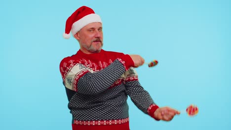Joyful-man-in-red-Christmas-sweater,-hat-holding-candy-striped-lollipops,-dancing-making-silly-faces