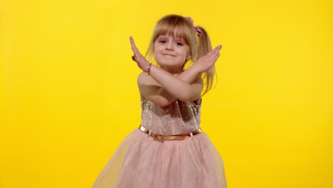 Kid-girl-looking-at-camera-crossed-hands-showing-stop-gesture-on-yellow-background.-Slow-motion