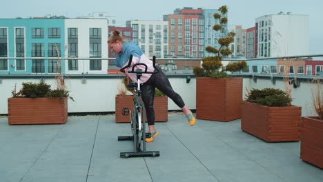 Sportliches-Mädchen-Macht-Akrobatische-Tricks-Auf-Dem-Fahrrad-Und-Trainiert-Auf-Einem-Stationären-Fahrradgerät-Im-Freien