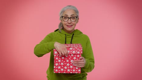 Elderly-granny-woman-opening-gift-box-expressing-disappointment,-dislike-gesture-to-awful-present