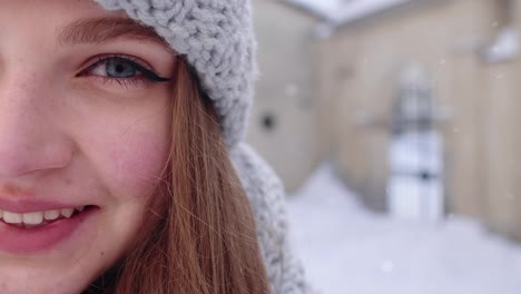Close-up-of-cheerful-positive-young-woman-face-smiling-to-camera-while-standing-outdoors-in-winter