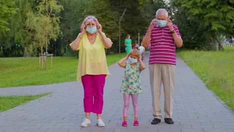 Senior-couple-grandmother-grandfather-with-granddaughter-wearing-medical-protective-mask-Coronavirus