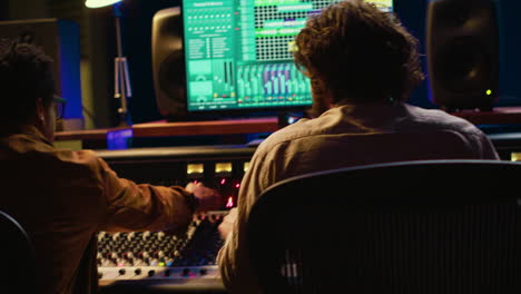 Audio-expert-and-musician-mixing-and-mastering-tracks-on-control-room-console