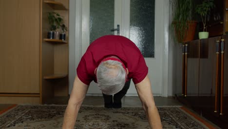 Senior-elderly-caucasian-man-in-sportswear-in-living-room,-making-morning-push-up-exercising-at-home