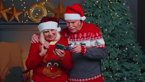 Großmutter-Einer-älteren-Familie,-Die-Mit-Kreditkarte-Und-Smartphone-Weihnachtsgeschenke-Einkauft