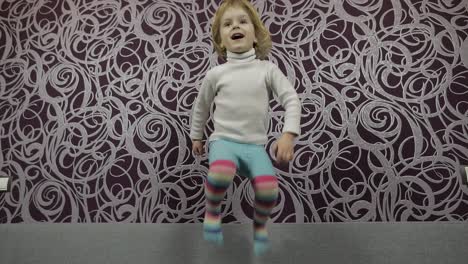 Little-happy-child-jumping-and-dancing-on-sofa-and-listening-music.-Slow-motion