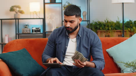 Rich-happy-Indian-man-using-calculator-counting-money-cash-salary-calculate-domestic-bills-at-home