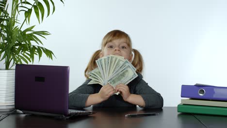 Child-girl-boss-earns-money.-Little-boss-kid-hold-much-dollars-cash-in-her-hands-in-the-office