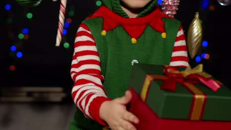 Kid-girl-in-Christmas-elf-Santa-Claus-helper-costume-getting,-receiving-surprise-gift-box,-happiness