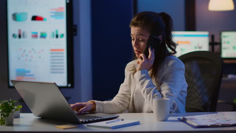 Woman-employee-speaking-at-phone-while-working-at-laptop