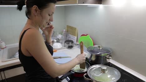 Schöne-Kaukasische-Frau-Telefoniert-Beim-Kochen