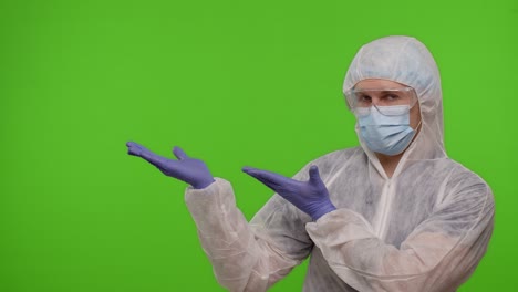 Medical-doctor-in-protective-PPE-suit-pointing-at-left-on-blank-space-on-chroma-key-background