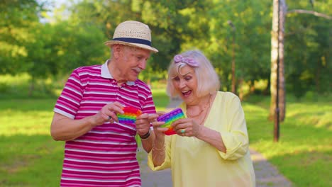 Senior-stylish-couple-grandmother-grandfather-squeezing-anti-stress-push-pop-it-popular-toy-game