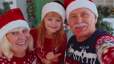 POV-shot-of-senior-grandparents-with-grandchild-girl-kid-taking-selfie-on-mobile-phone-on-Christmas