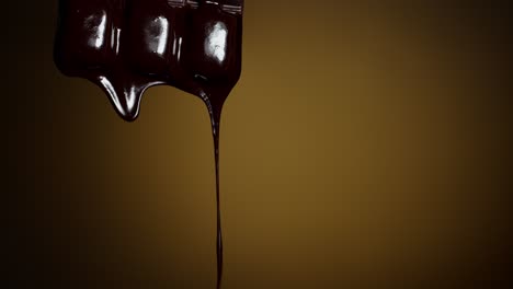 Chocolate-bar-with-melted-chocolate-syrup-dripping-flowing-over-dark-brown-background,-confectionery