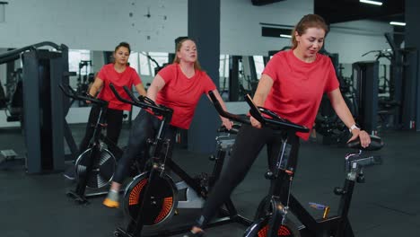 Athletic-women-group-making-stretching-training-on-spinning-stationary-bike-routine-in-gym-indoors