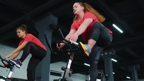 Gruppe-Sportlicher-Mädchen,-Die-Aerobic-Trainingsübungen-Auf-Dem-Fahrradergometer-Im-Fitnessstudio-Durchführen