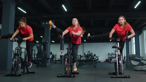 Gesunde-Kaukasische-Gruppe-Von-Frauen-Trainieren-Auf-Einem-Stationären-Fahrrad-Im-Fitnessstudio